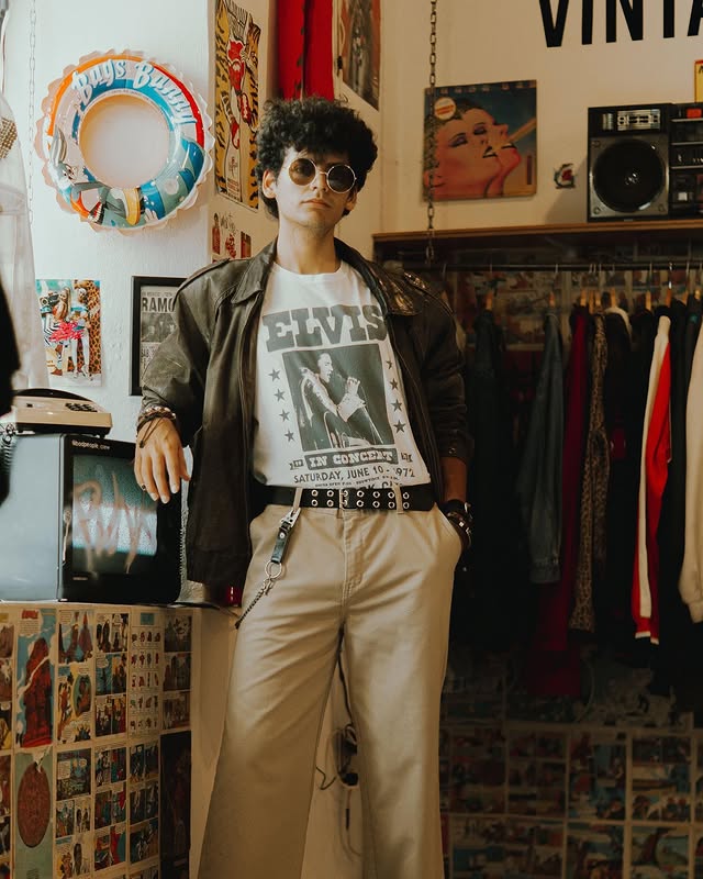 Modelo con chamarra de piel y playera Elvis junto a teléfono vintage
