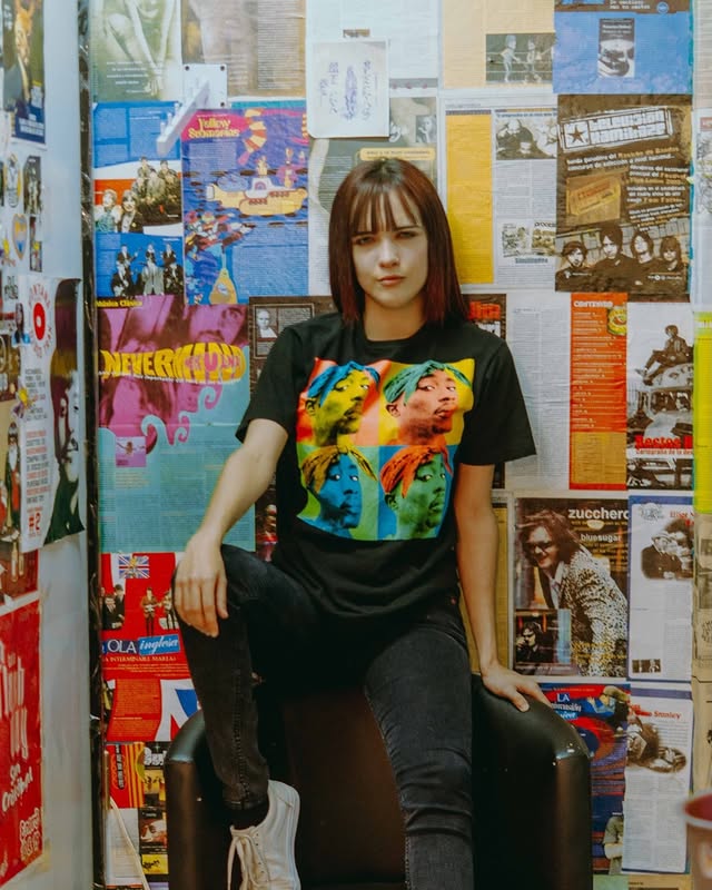 Modelo con playera gráfica pop art frente a pared de fanzines