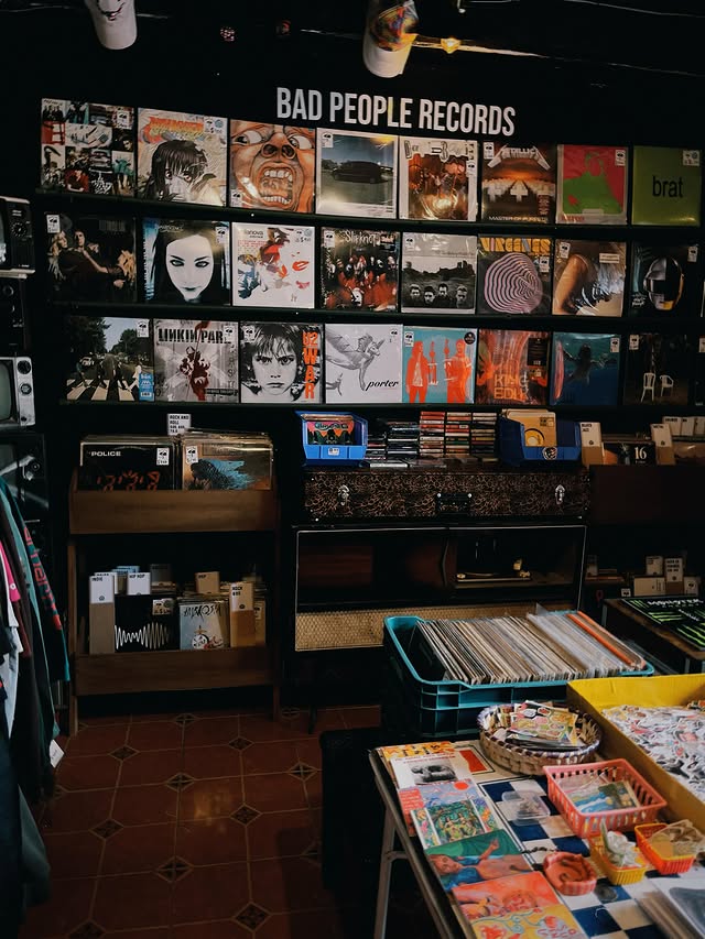 Pared de vinilos curados bajo el letrero Bad People Records